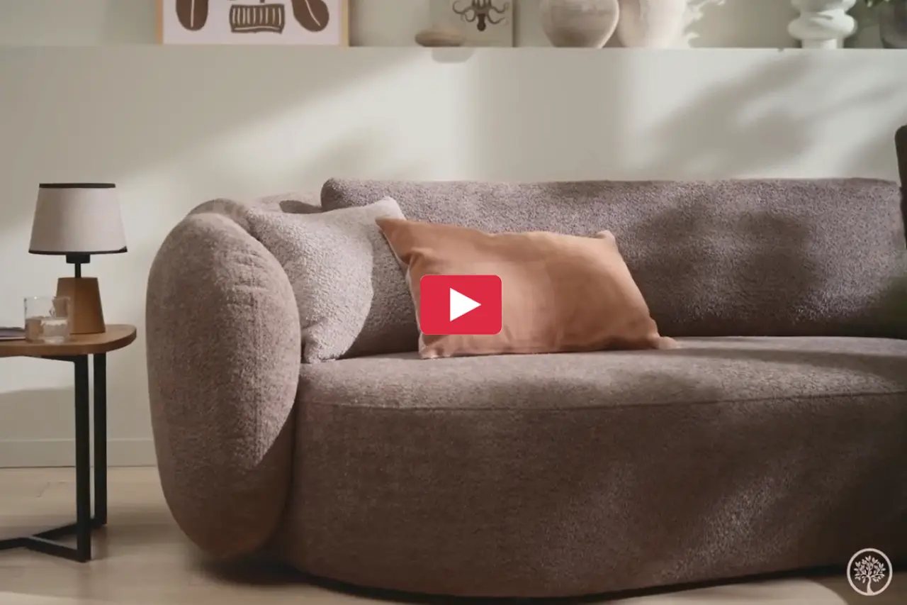 Bequemes Sofa mit weichem Bouclé-Stoff und dekorativem Kissen in warmen Farben. Daneben steht ein Beistelltisch mit Lampe. Moderne Polstermöbel für gemütliches Wohnen und stilvolle Einrichtung.